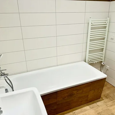 Badezimmer der Wohnung in Leipzig-Plagwitz mit Badewanne, Handtuchheizung und Fliesen in Holzoptik