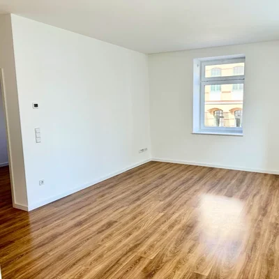 Helles Wohnzimmer der 2-Zimmer-Wohnung in Leipzig-Plagwitz mit großen Fenstern und Laminatboden