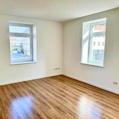 Wohnzimmer der Wohnung in Leipzig-Plagwitz mit mehreren Fenstern und Laminatboden